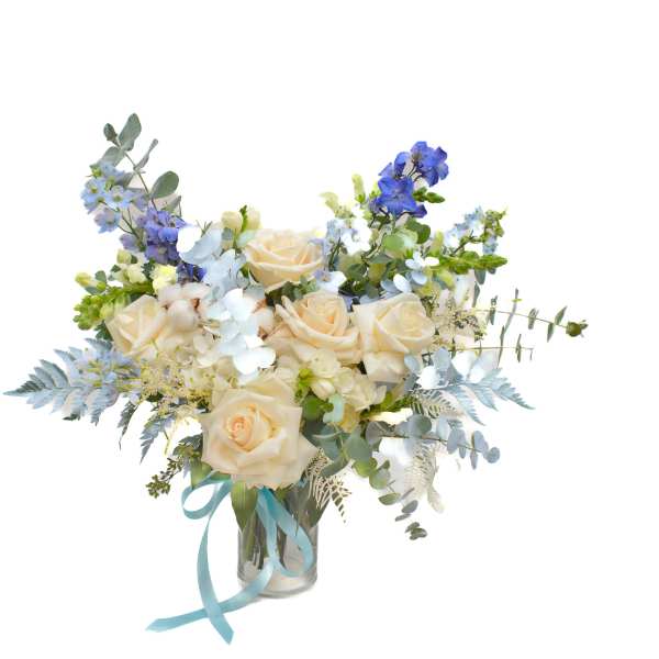 Bouquet of cream roses and blue flowers in a glass vase