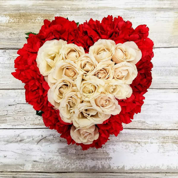 Heart-shaped bouquet of cream roses surrounded by red carnations