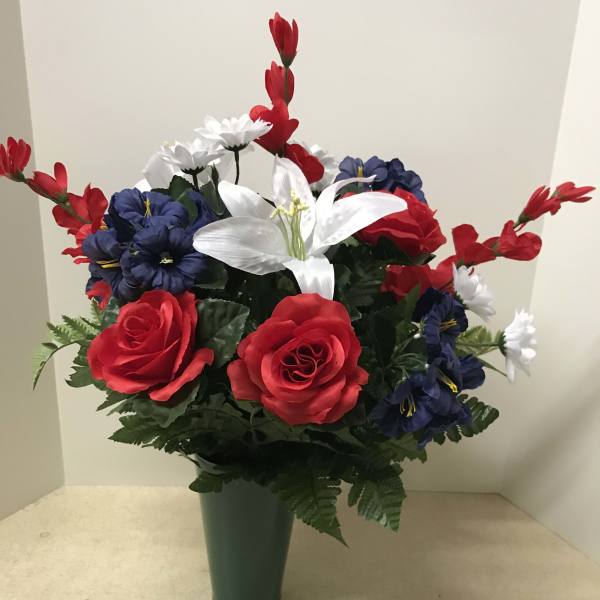 Artificial red, white, and blue flowers arranged in a green vase