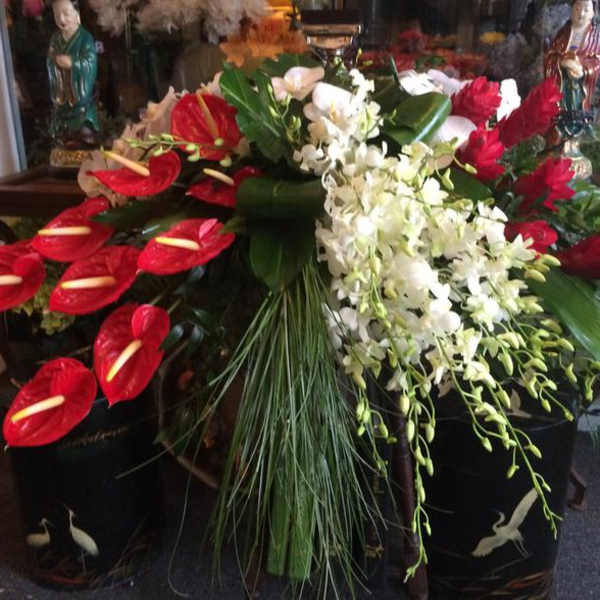 Large floral arrangement with red anthuriums and white orchids in black containers