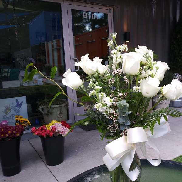 White rose bouquet in a glass vase with a white ribbon
