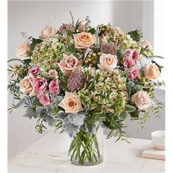 Bouquet of peach and pink roses with hydrangeas in a clear glass vase
