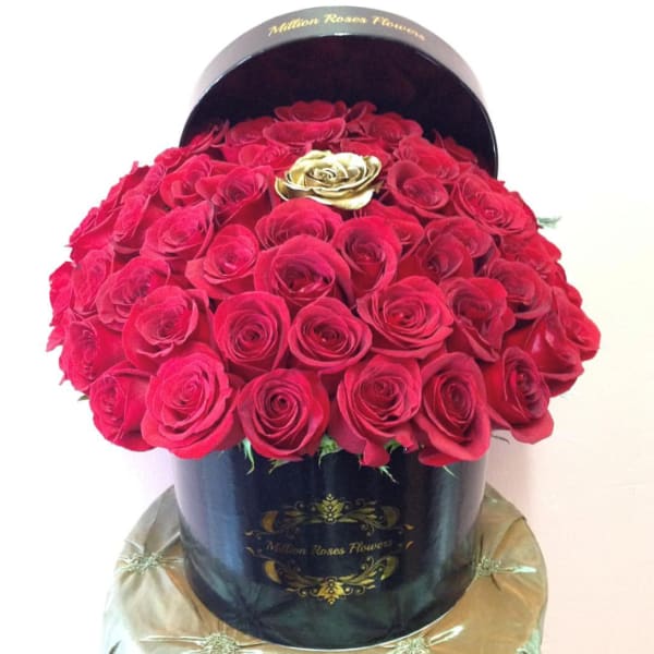 Round box filled with red roses and a gold rose accent