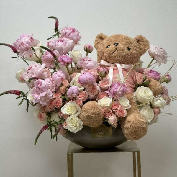 Pink and white flower arrangement with a teddy bear in a bowl vase