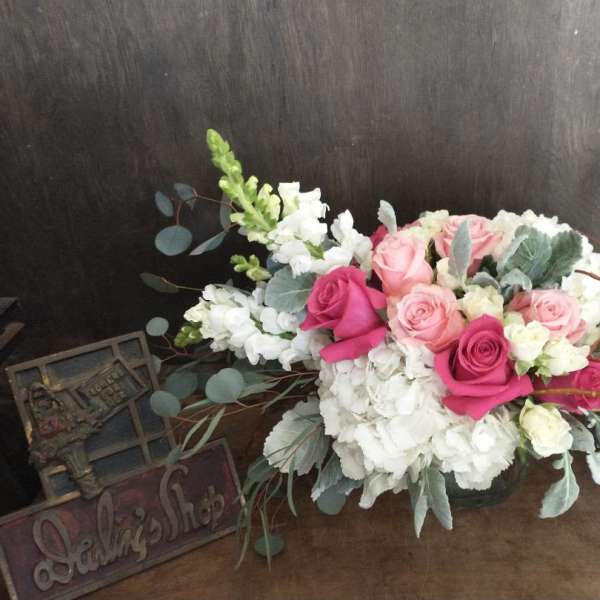 Pink and white rose arrangement with eucalyptus in a low container