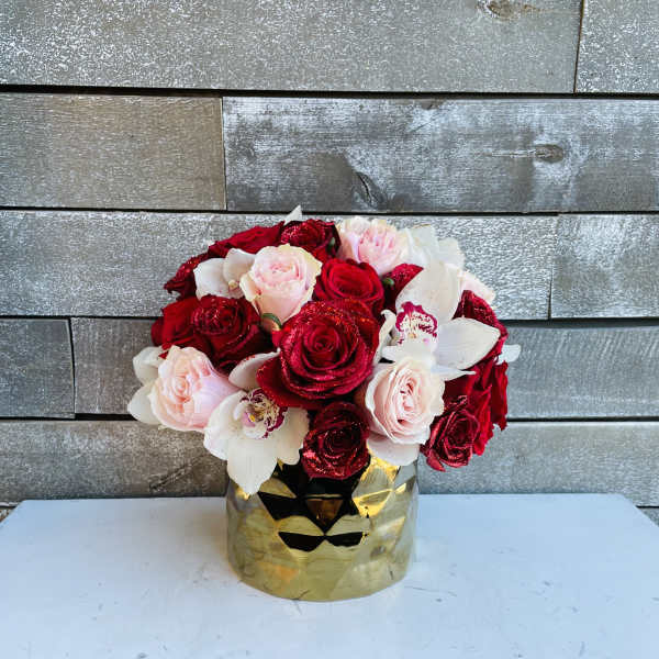 Bouquet of red, pink, and white roses in a gold vase