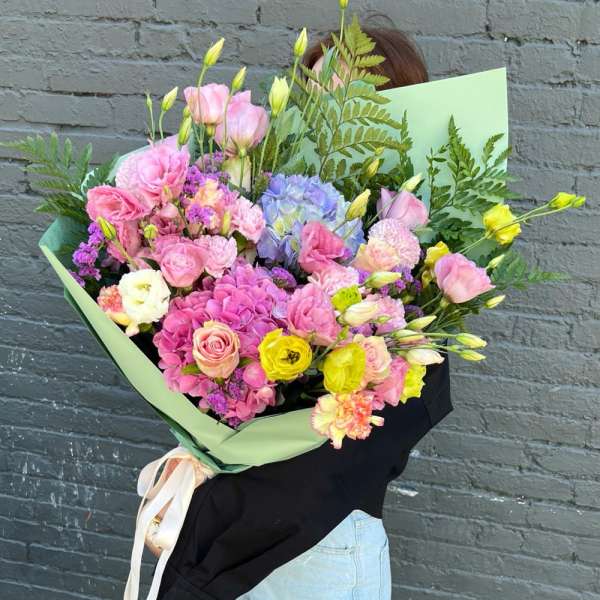 Large mixed bouquet of pink, purple, and yellow flowers wrapped in green paper