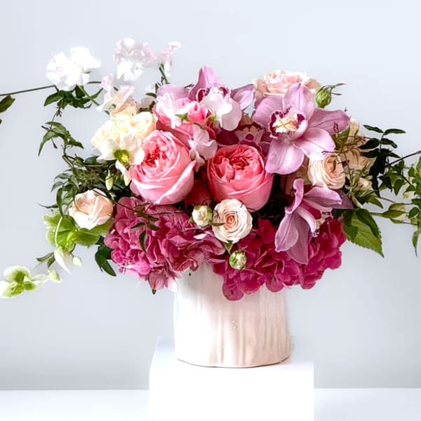 Pink and white floral arrangement in a pale vase