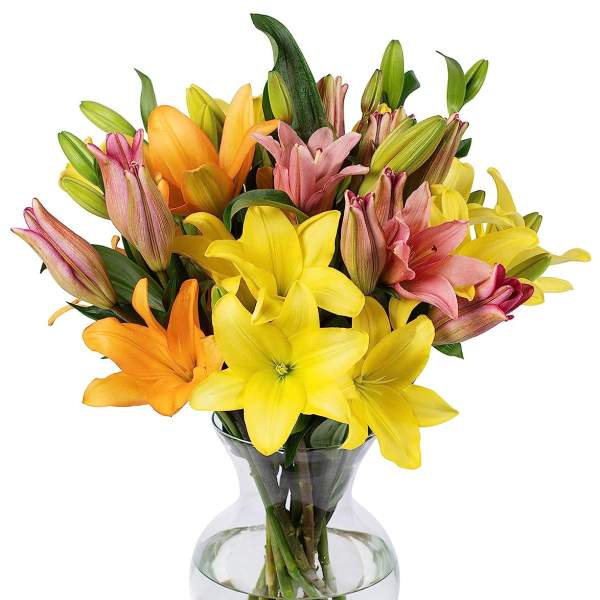 Mixed bouquet of yellow, orange, and pink lilies arranged in a clear glass vase