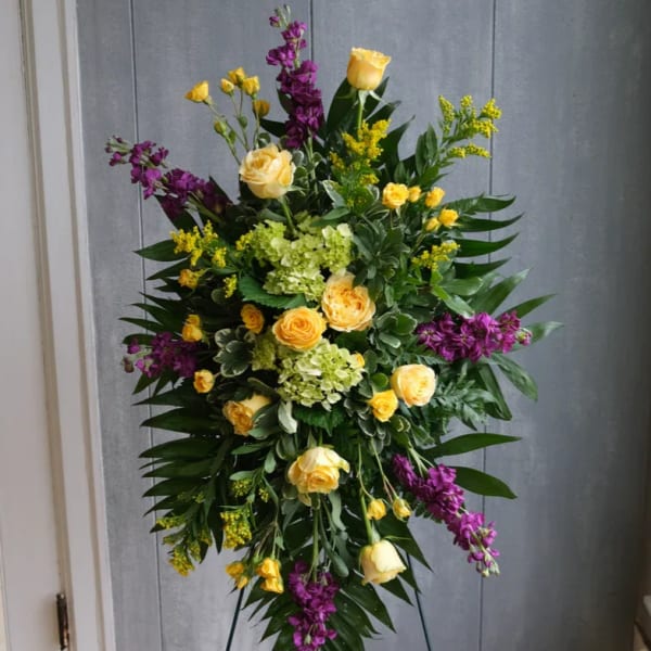 Tall standing floral spray with yellow roses and purple flowers