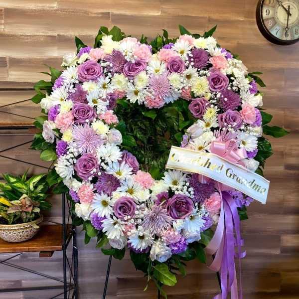 Heart-shaped floral wreath with pink, purple, and white flowers on an easel