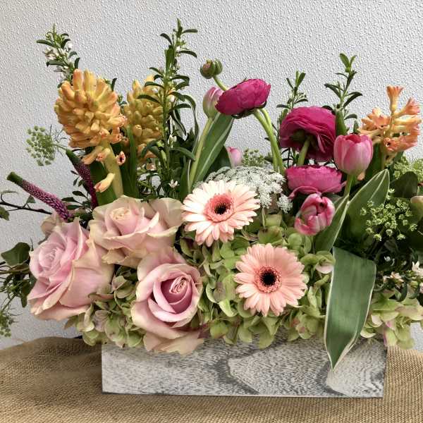 Mixed bouquet with pink roses, gerbera daisies, tulips, and hyacinths in a rectangular vase