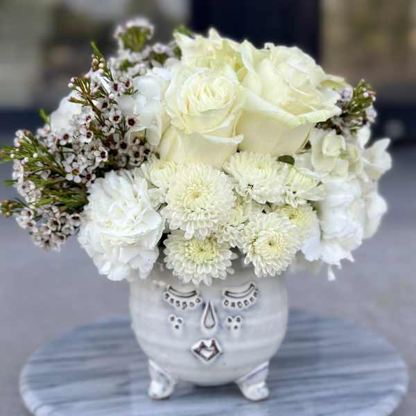 White roses and chrysanthemums arranged in a decorative ceramic vase