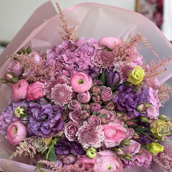 Pink and purple mixed bouquet with roses and ranunculus in pink wrap