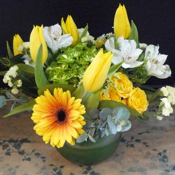 Yellow tulips and white flowers in a low green bowl arrangement