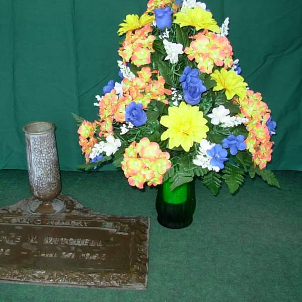Colorful floral arrangement beside a memorial plaque and vase