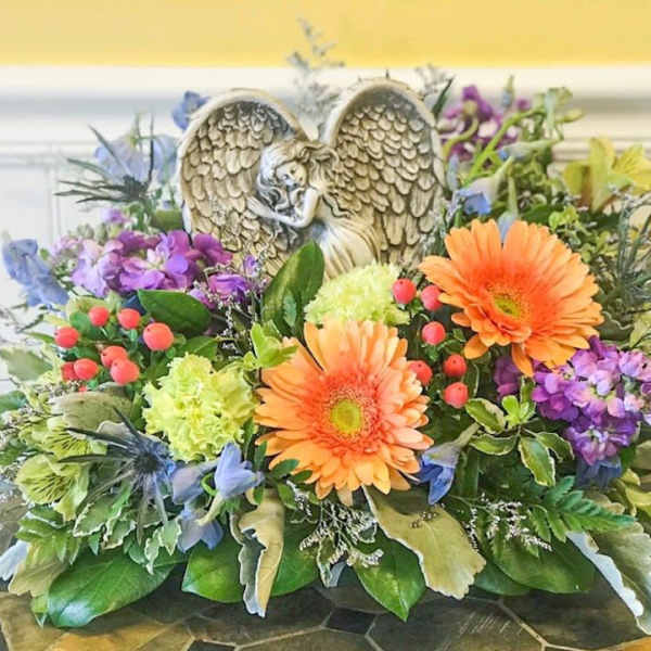 Colorful floral arrangement with an angel figurine centerpiece