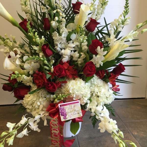 Large red and white floral standing arrangement in a white container