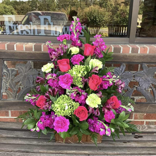 Pink and magenta floral arrangement in a wooden basket
