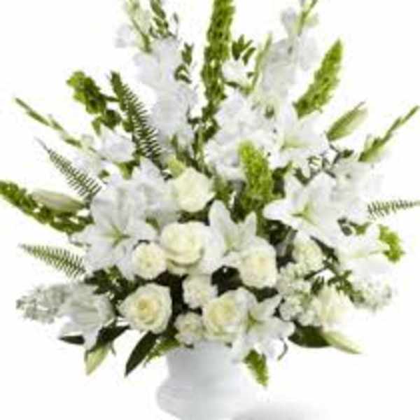 White floral arrangement in a white vase with tall green accents