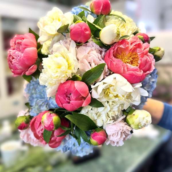 Handheld bouquet of pink, white, yellow, and blue flowers