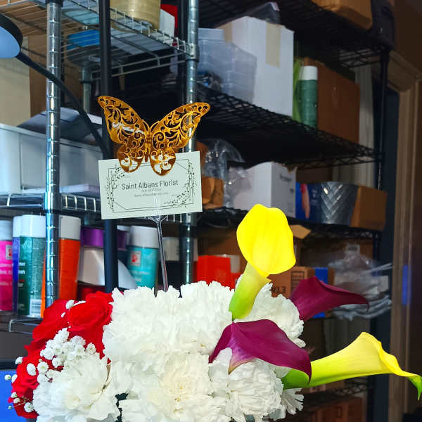 Flower arrangement in a black gift bag with calla lilies and roses, plus a chocolate box