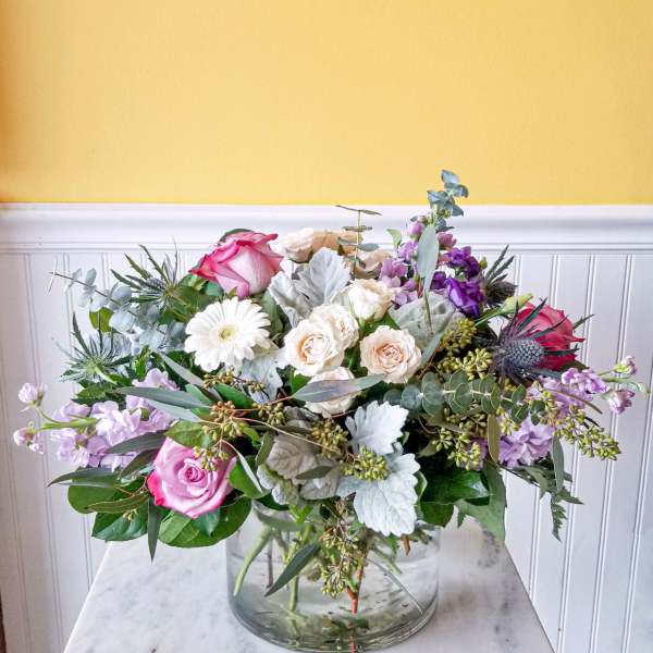 Mixed bouquet of pink, white, and lavender flowers in a glass vase
