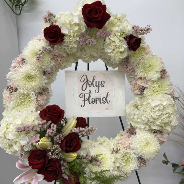 Large floral wreath with white blooms and red roses on an easel