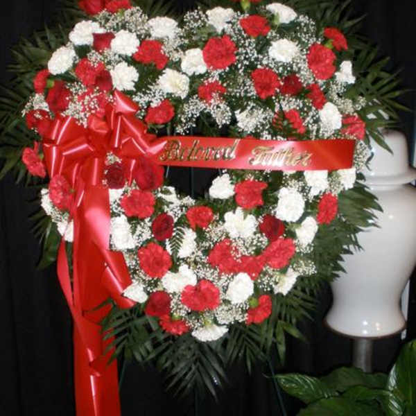 Heart-shaped red and white floral wreath with a red ribbon
