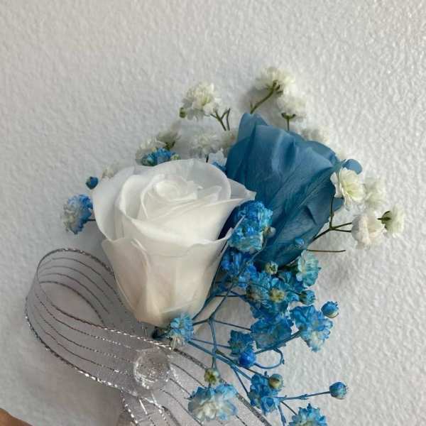 White rose boutonniere with blue baby's breath and silver ribbon