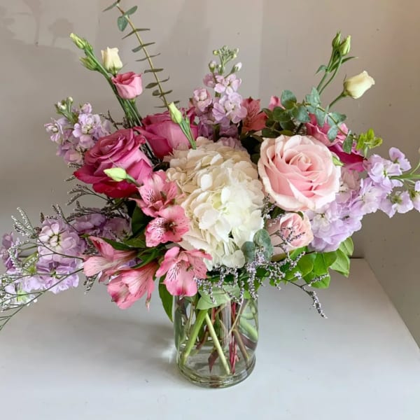 Pink and white roses with hydrangea in a clear glass vase