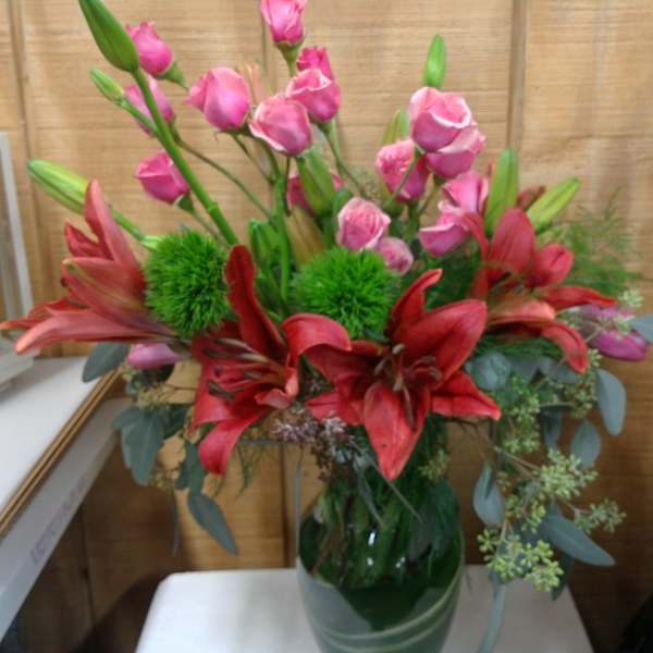 Pink roses and red lilies arranged in a glass vase