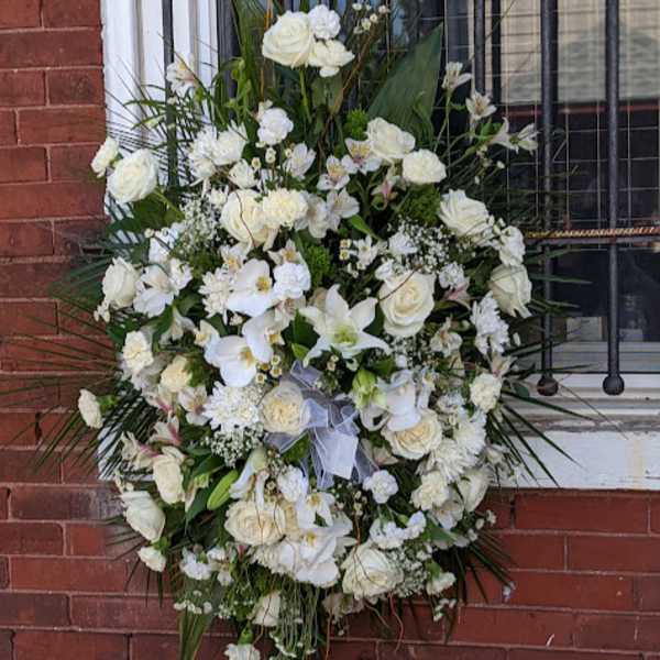 Large white funeral spray with roses and orchids