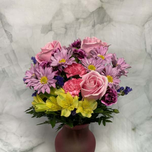 Pink and purple mixed bouquet in a burgundy vase