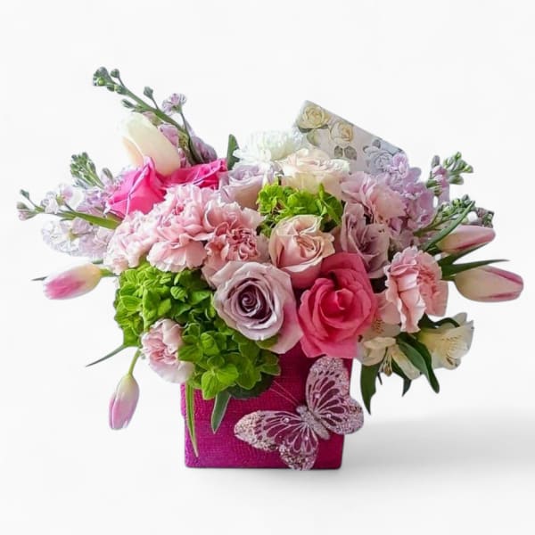 Pink and pastel mixed flower arrangement in a pink cube container with a butterfly accent.