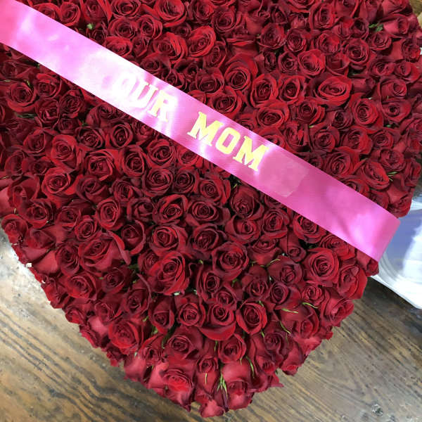 Heart-shaped bouquet of red roses with a pink ribbon