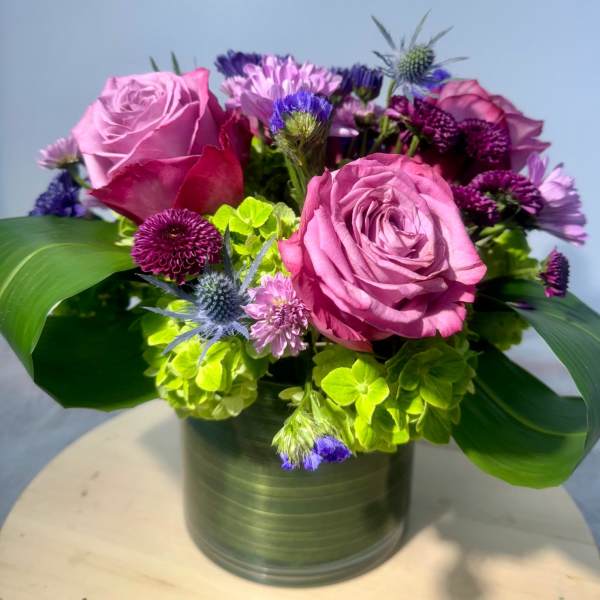 Pink roses and purple flowers arranged in a metal vase