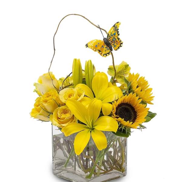 Yellow floral arrangement in a square glass vase with a butterfly pick