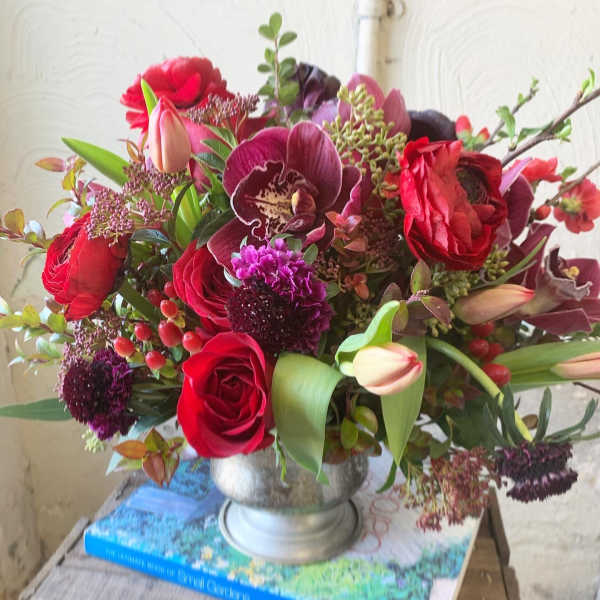 Bouquet of red roses and purple orchids in a silver vase