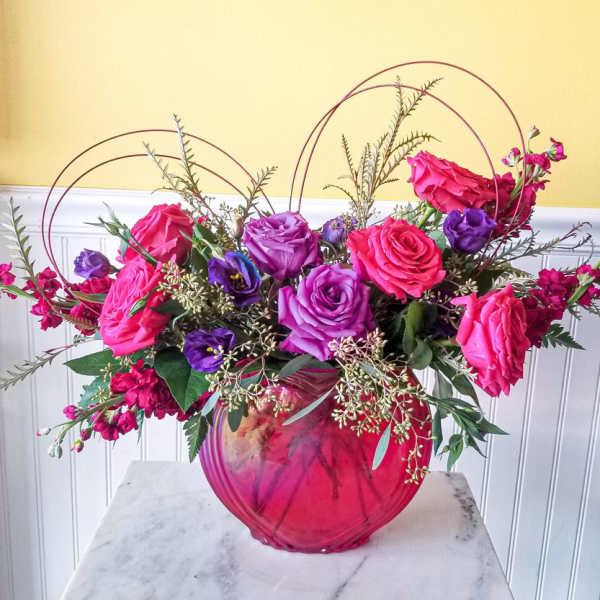 Pink and purple roses arranged in a round glass vase