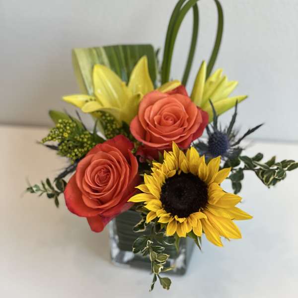 Bouquet of orange roses and a sunflower in a glass vase