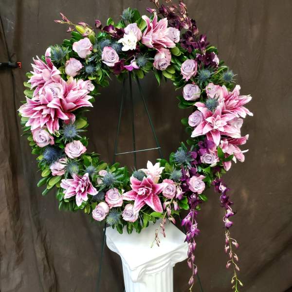 Circular floral wreath with pink lilies and lavender roses on a stand