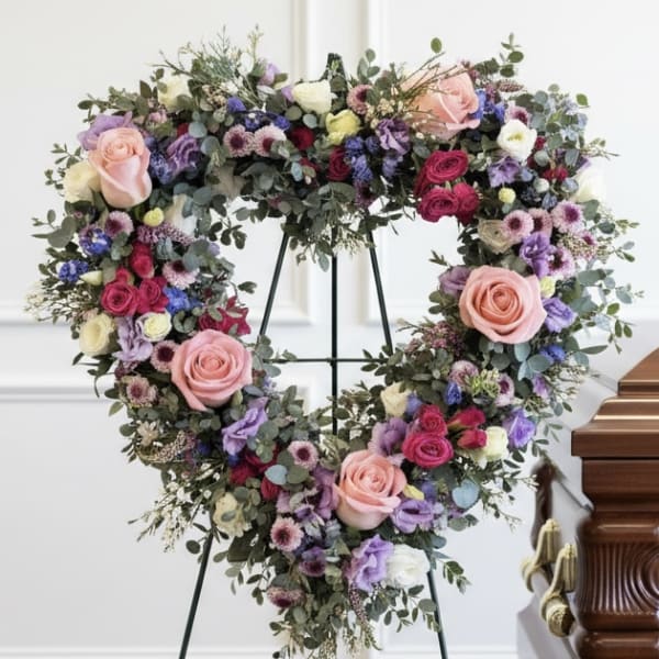 Heart-shaped floral wreath with pink roses and purple blooms