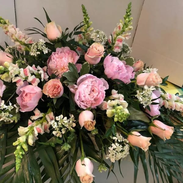 Pink roses and peonies arranged with snapdragons and greenery