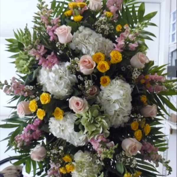 Large standing floral spray with pink roses, white hydrangeas, and yellow blooms