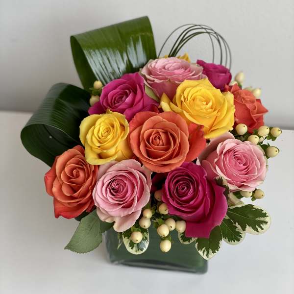 Colorful rose bouquet in a dark green box with decorative leaves