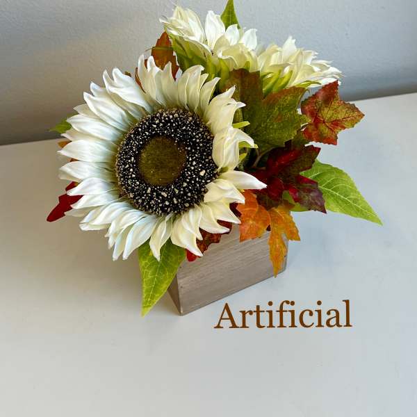 Artificial sunflower arrangement in a wooden box with autumn leaves
