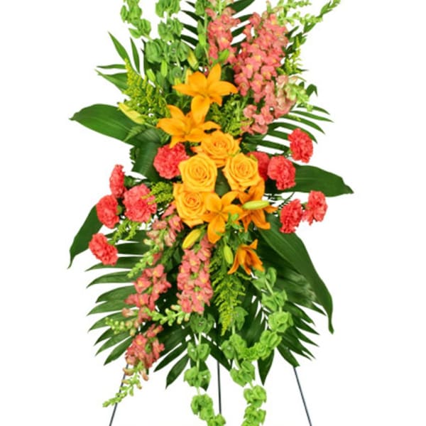 Tall standing spray with orange lilies, yellow roses, pink flowers, and green Bells of Ireland on an easel