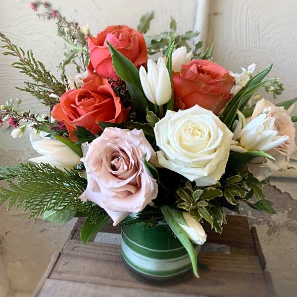 Mixed roses and white tulips in a green glass vase