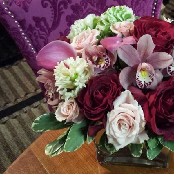 Bouquet of pink and burgundy flowers in a square glass vase